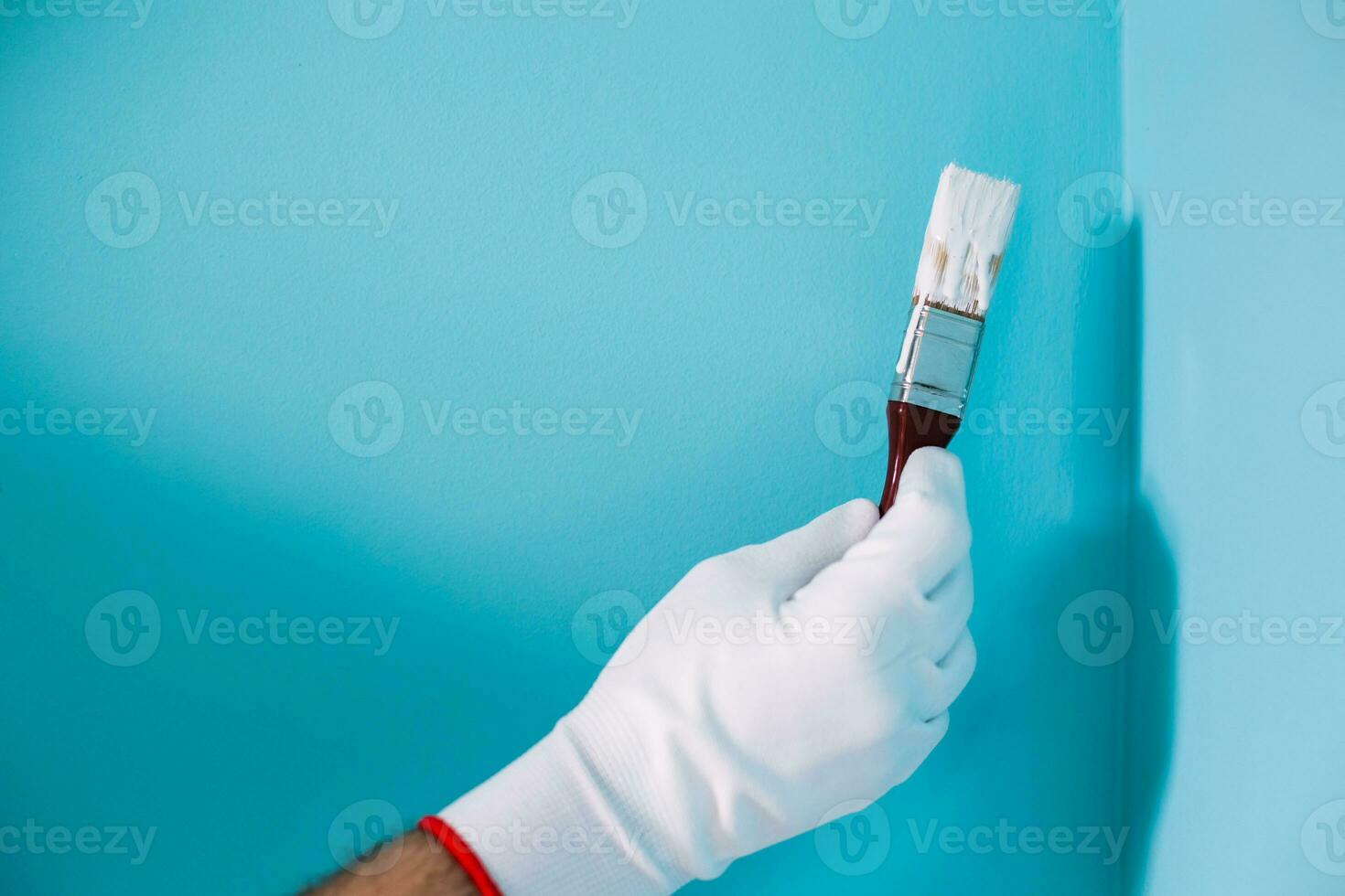 beeld van Mens Holding penseel in voorkant van blauw muur. foto