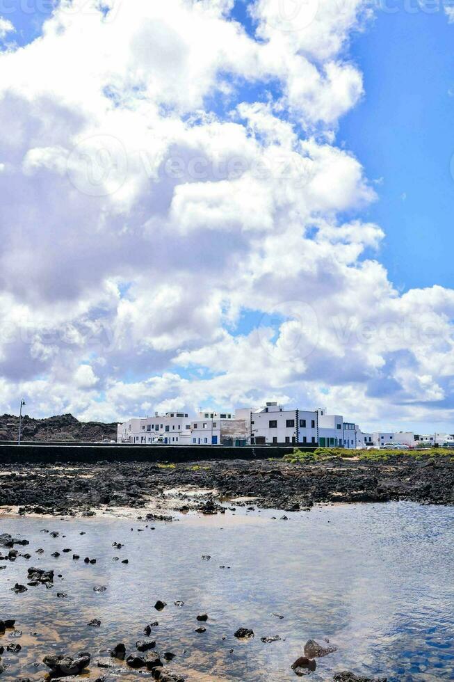 een strand met rotsen en een weinig gebouwen foto