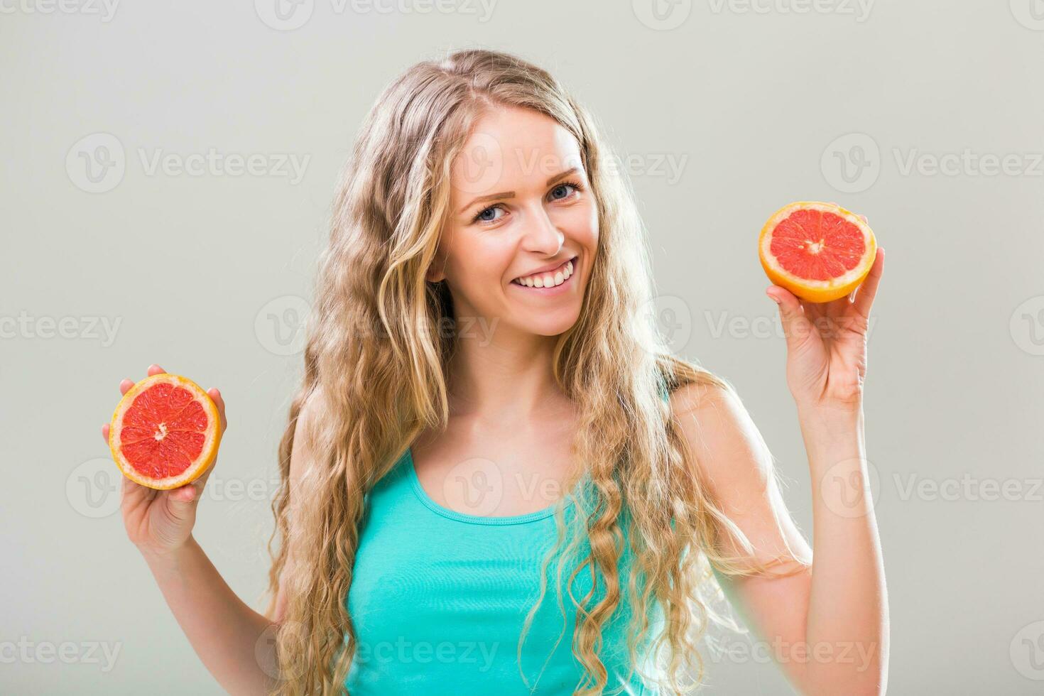 mooi jong vrouw tonen plakjes van grapefruit Aan grijs achtergrond. foto