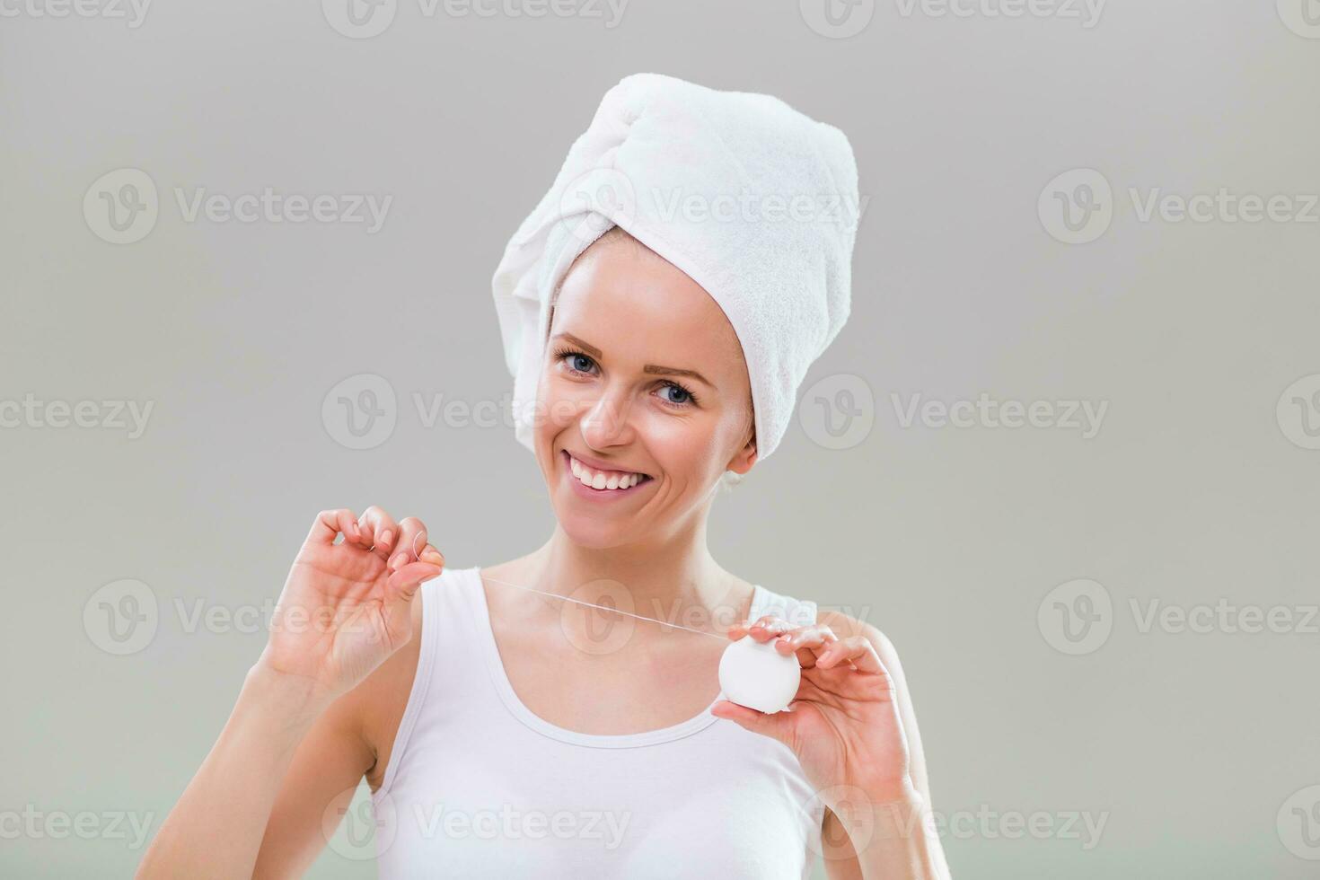 mooi jong vrouw gebruik makend van tandheelkundig floss Aan grijs achtergrond. foto