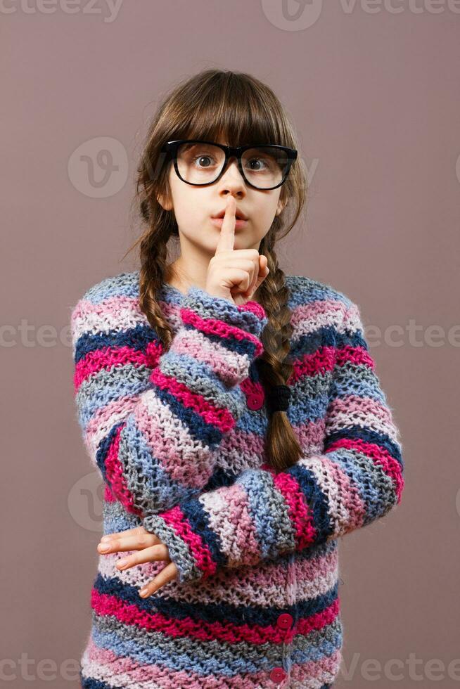 weinig nerd meisje met een vinger Aan haar lippen foto