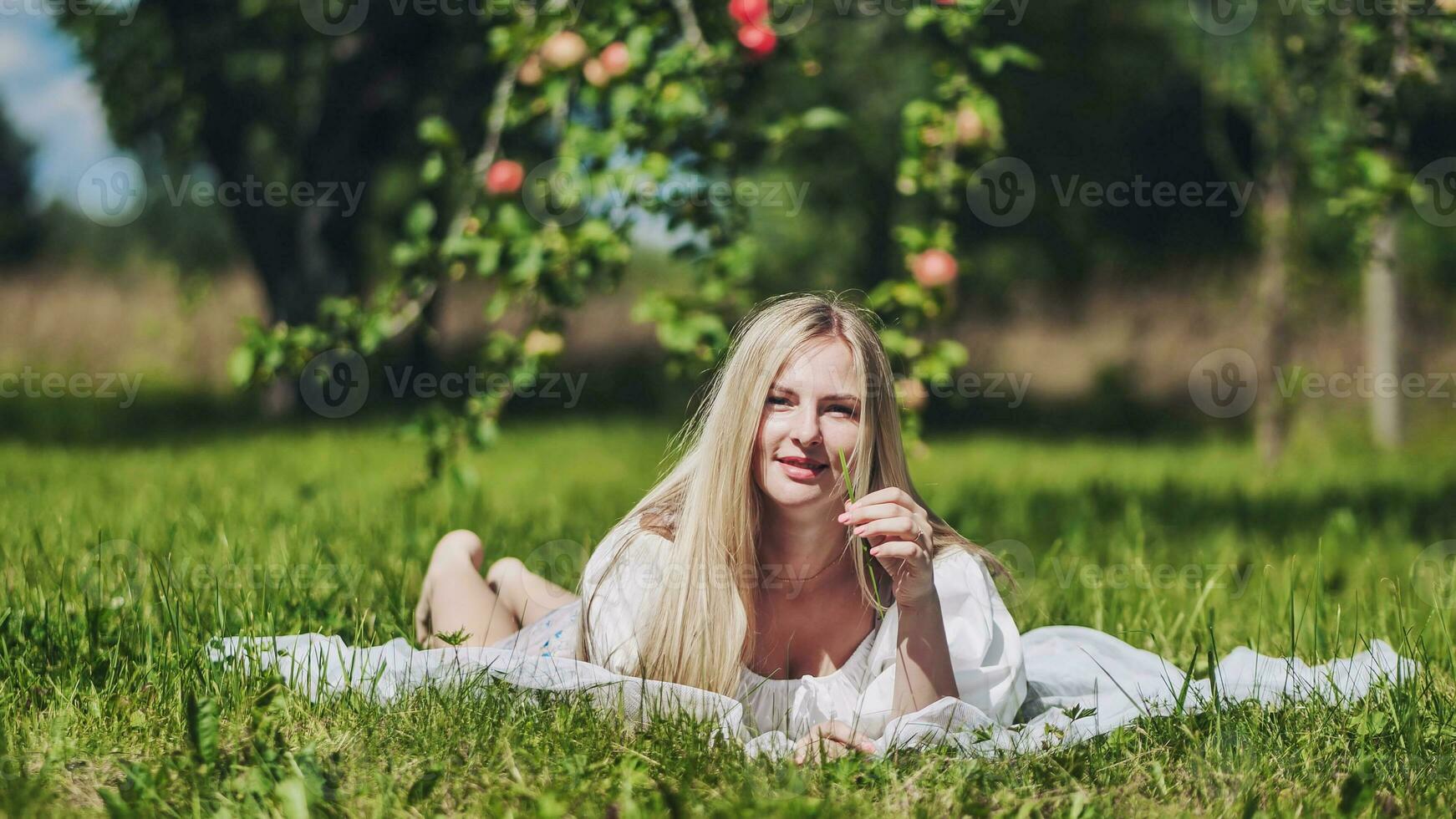 een blond meisje leugens in een opruimen in een appel boomgaard. foto