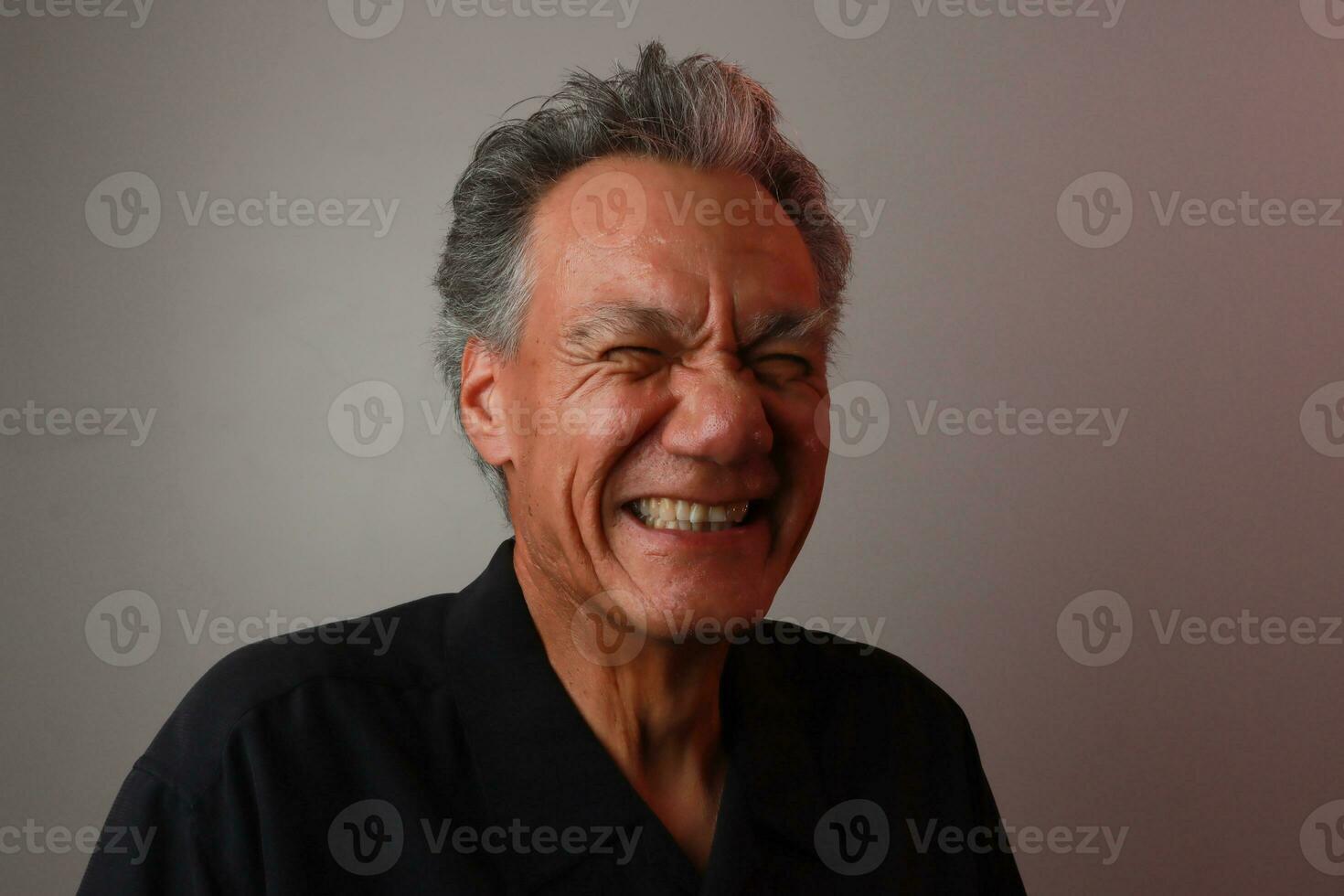 ouder volwassen Mens tegen een grijs achtergrond breken uit in gelach foto