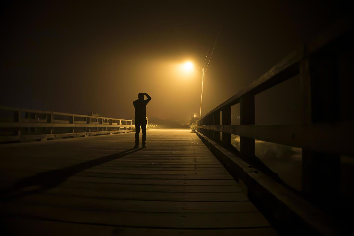 silhouet van een man onder een straatlantaarn foto