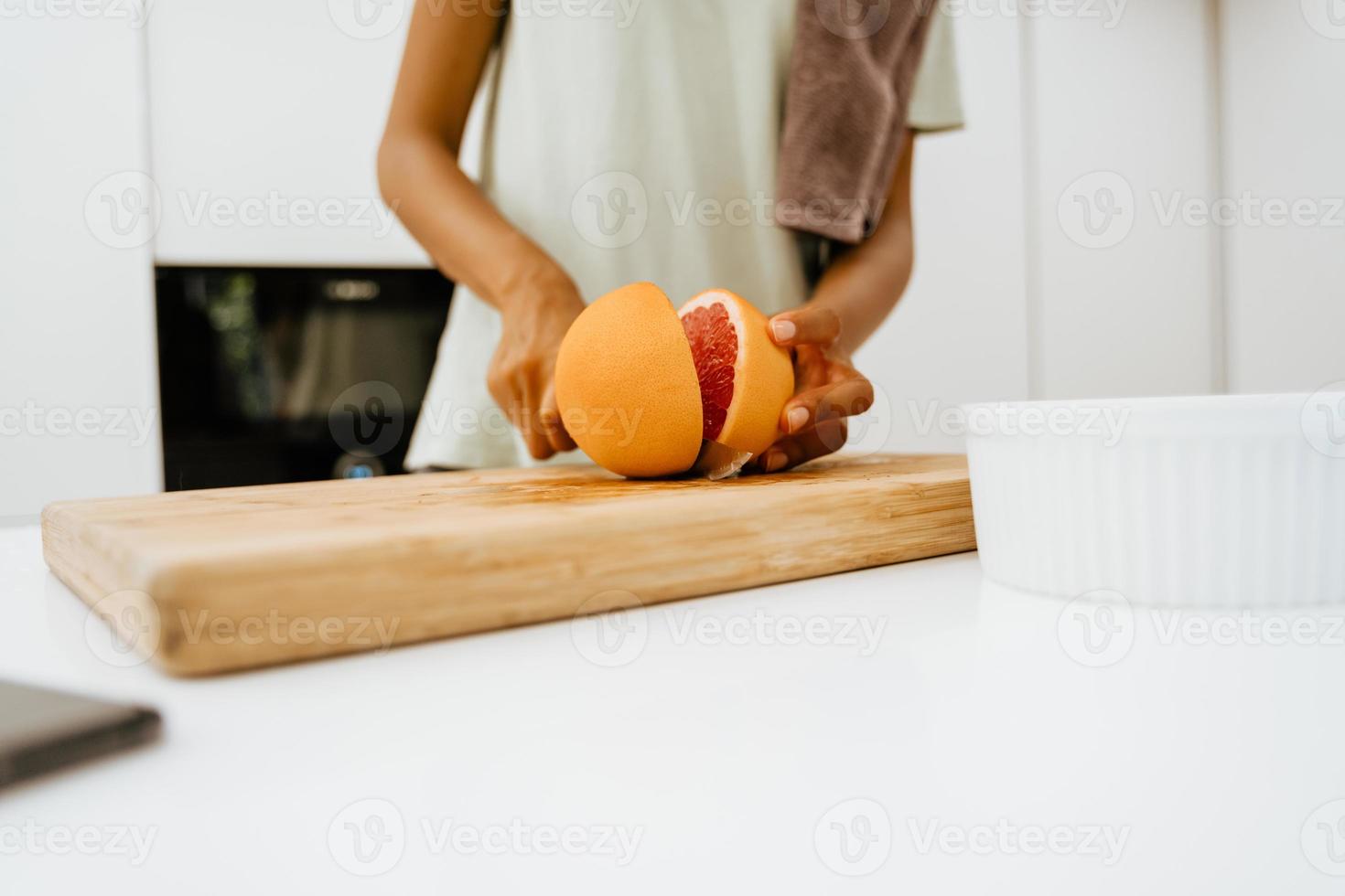 zwarte jonge vrouw die grapefruit snijdt tijdens het koken in de keuken foto