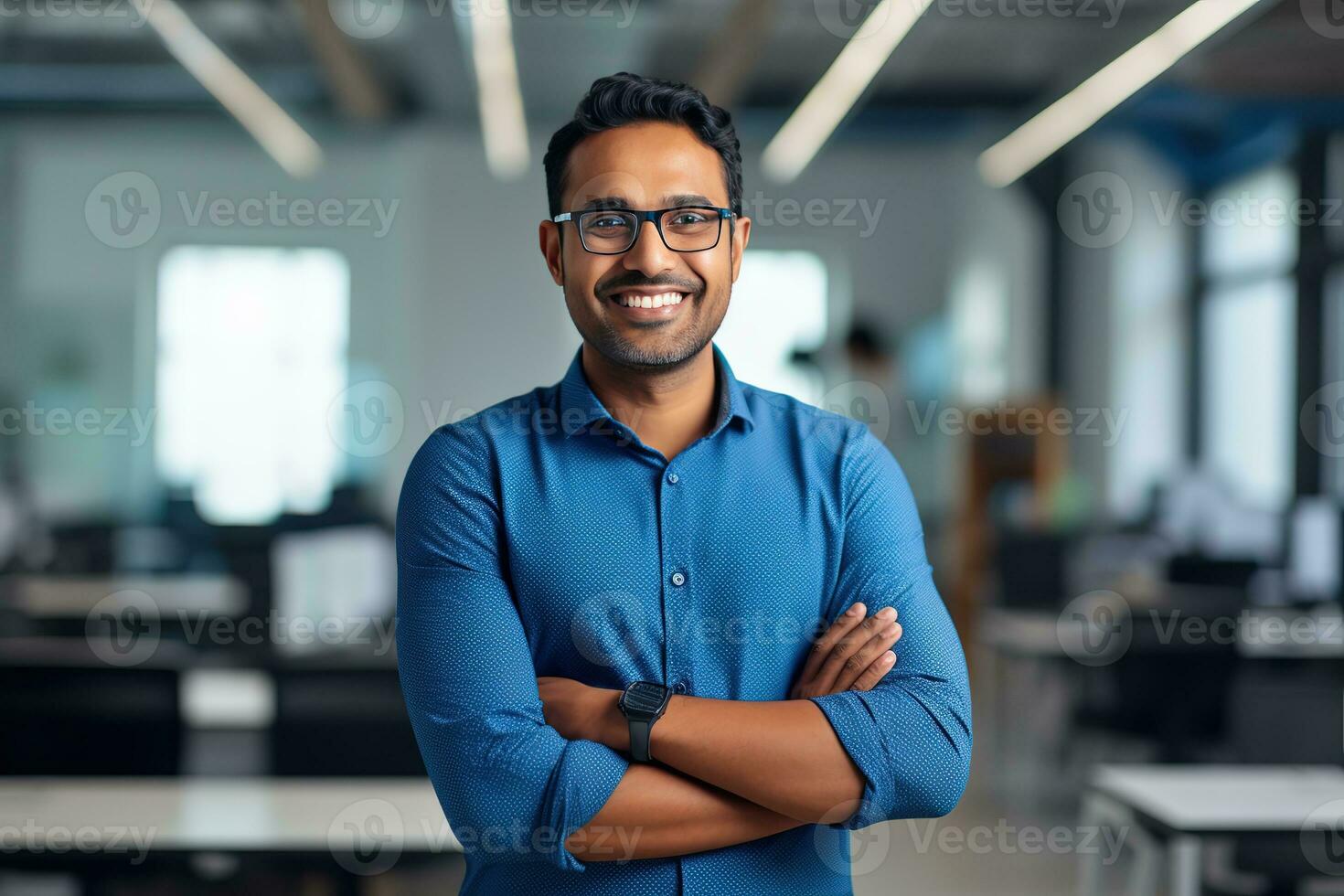 ai gegenereerd een jong Indisch mannetje ontwerper, ingenieur, architect wie is vervelend bril en een blauw overhemd glimlachen staand in de kantoor en op zoek Bij de camera foto