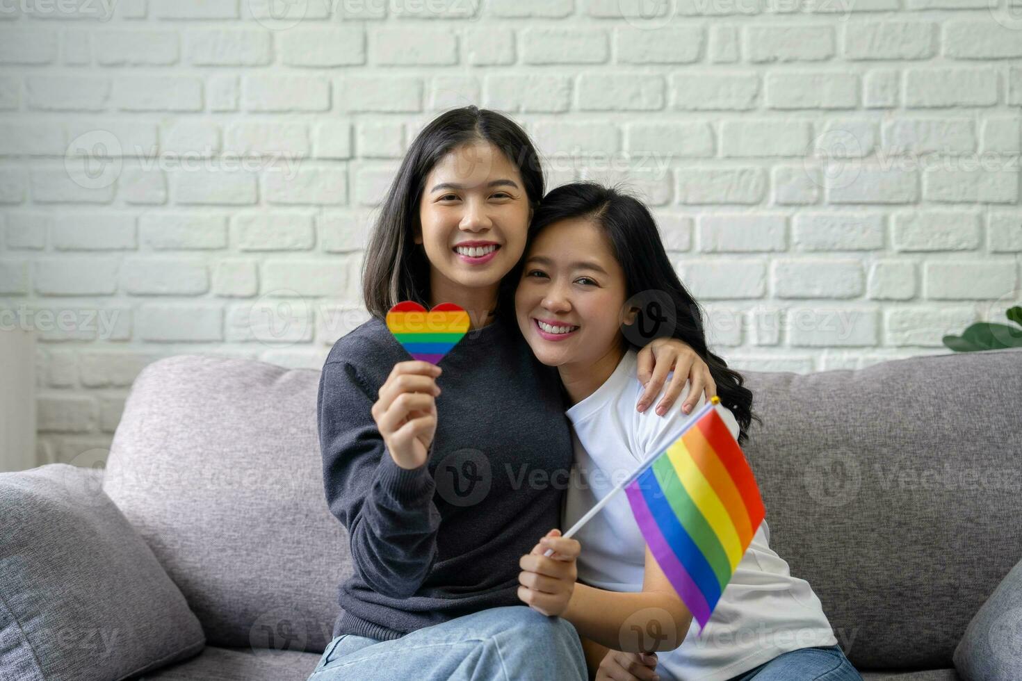 aantrekkelijk Aziatisch lesbienne paar Holding lgbt vlag in leven kamer Bij huis met glimlachen gezichten foto