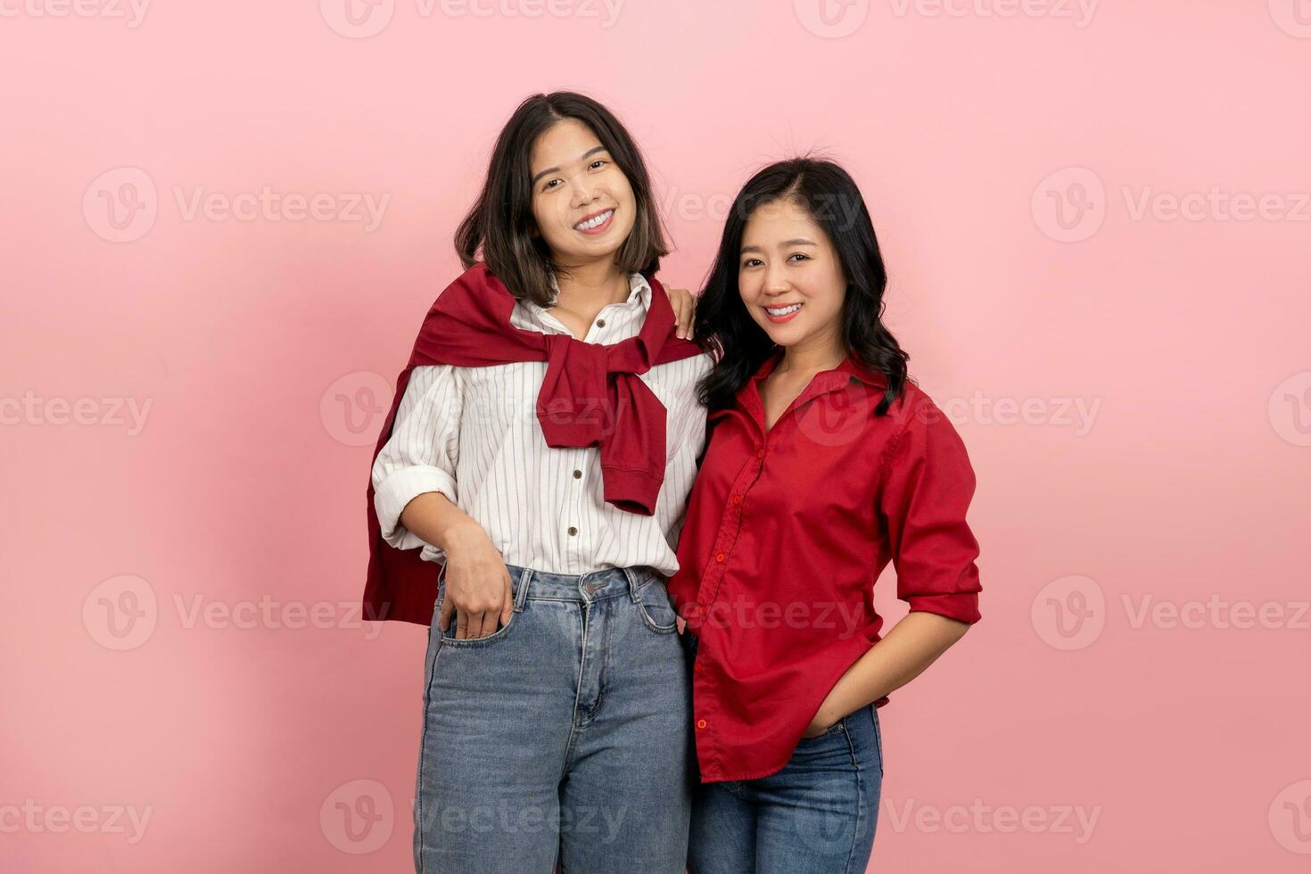 Aziatisch meisje in elegant kleren poses Aan een roze achtergrond. aantrekkelijk vrouw in rood overhemd en jeans. mooi vrouw in wit overhemd en jeans .zij keek Bij de camera samen. foto