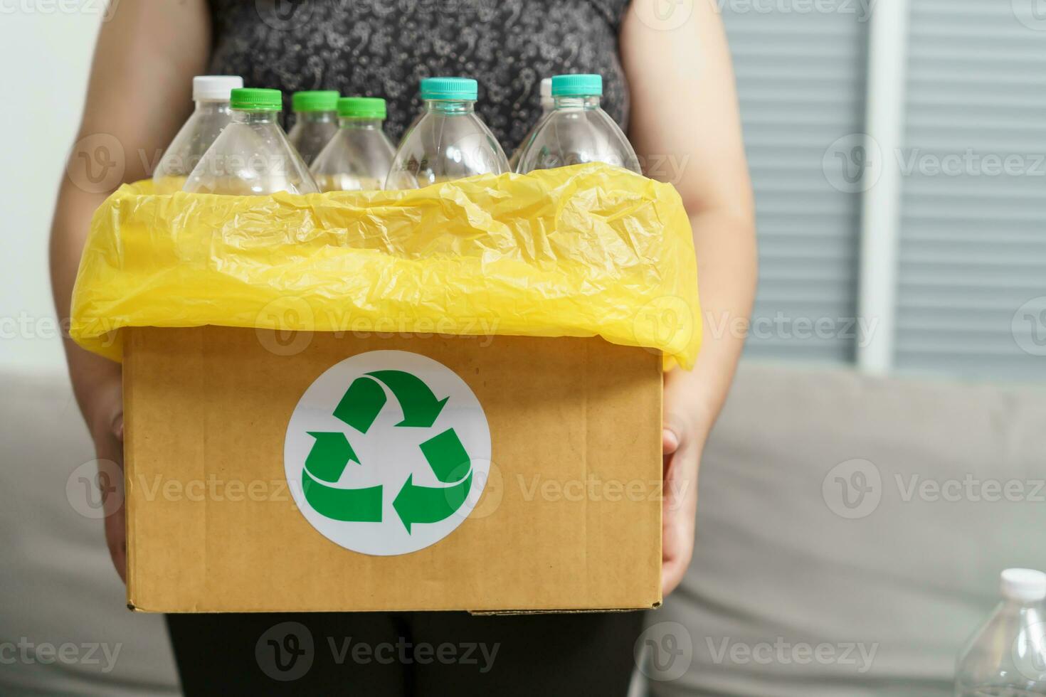 huis recycle eco groen nul concept vrouw het werpen leeg plastic fles in recycling bak met geel vuilnis Tassen Bij huis. foto