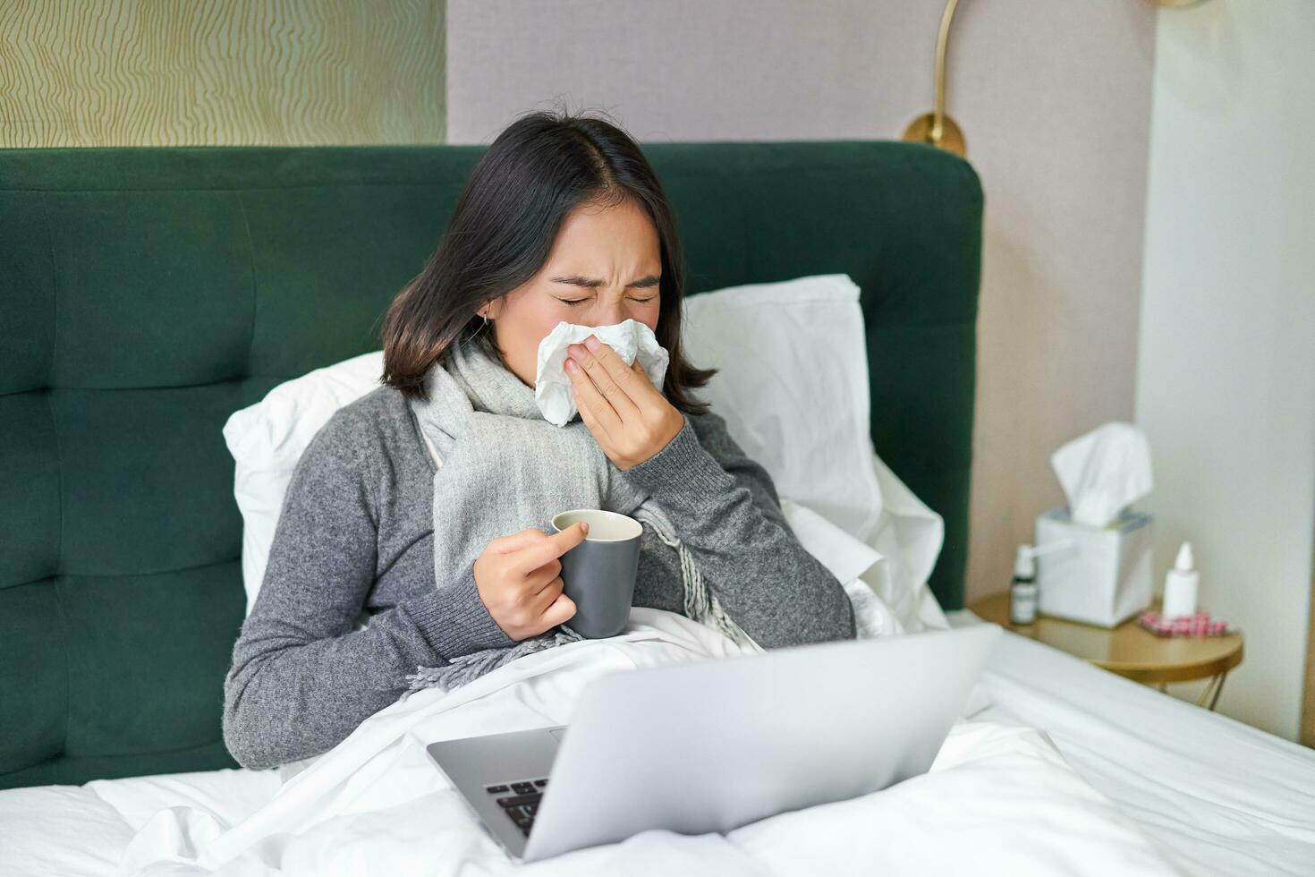 vrouw met koud, hebben griep, blijven in bed, niezen in servet, vloeibaar neus- en influenza symptomen foto