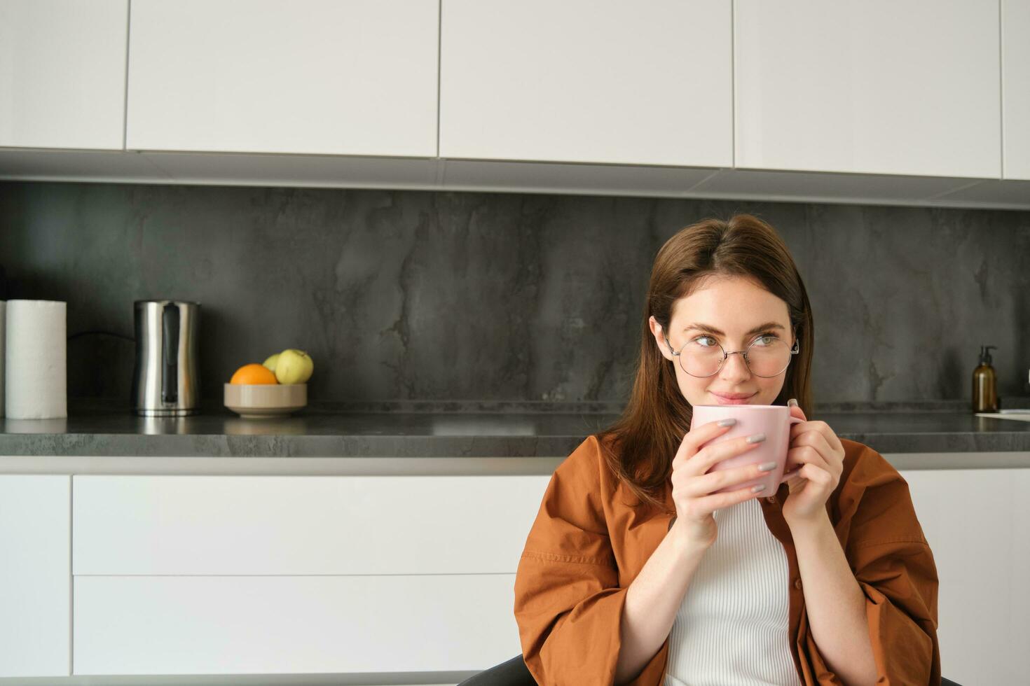 portret van brunette vrouw in keuken, Holding kop van thee, drinken aromatisch koffie Bij huis en genieten van kalm, knus dag uit foto