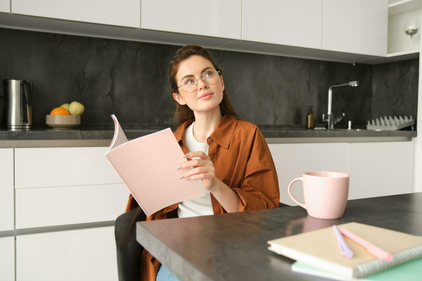 portret van jong vrouw werken van huis, eigen baas ondernemer lezing haar documenten, zittend Bij huis in keuken, vervelend bril foto