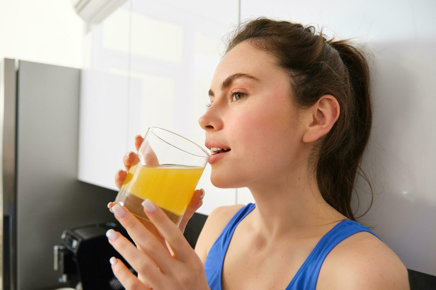 mooi vrouw drinken een biologisch oranje sap. fit jong vrouw drinken van glas. gezond meisje genieten ontgiften drinken en op zoek weg foto