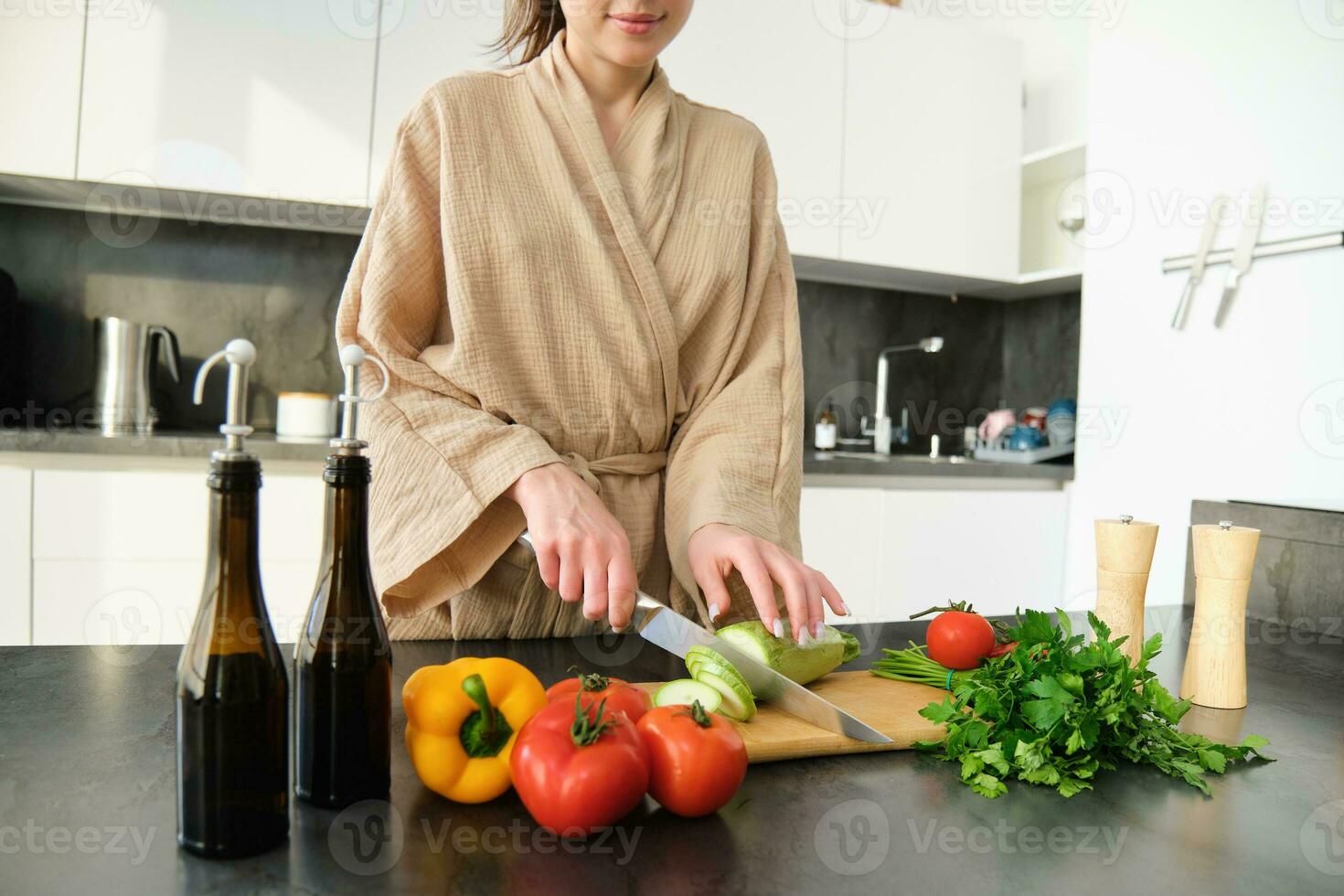 dichtbij omhoog portret van vrouw handen, vrouw vervelend gewaad, snijdend groenten Aan hakken bord, Koken veganistisch diner, vegetarisch maaltijd voor familie, staand in keuken foto