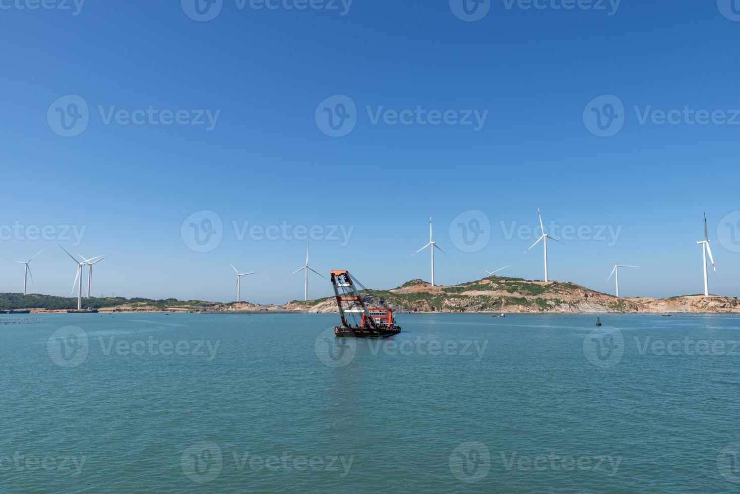 op het eiland midden in de zee staan veel windturbines onder de blauwe lucht foto