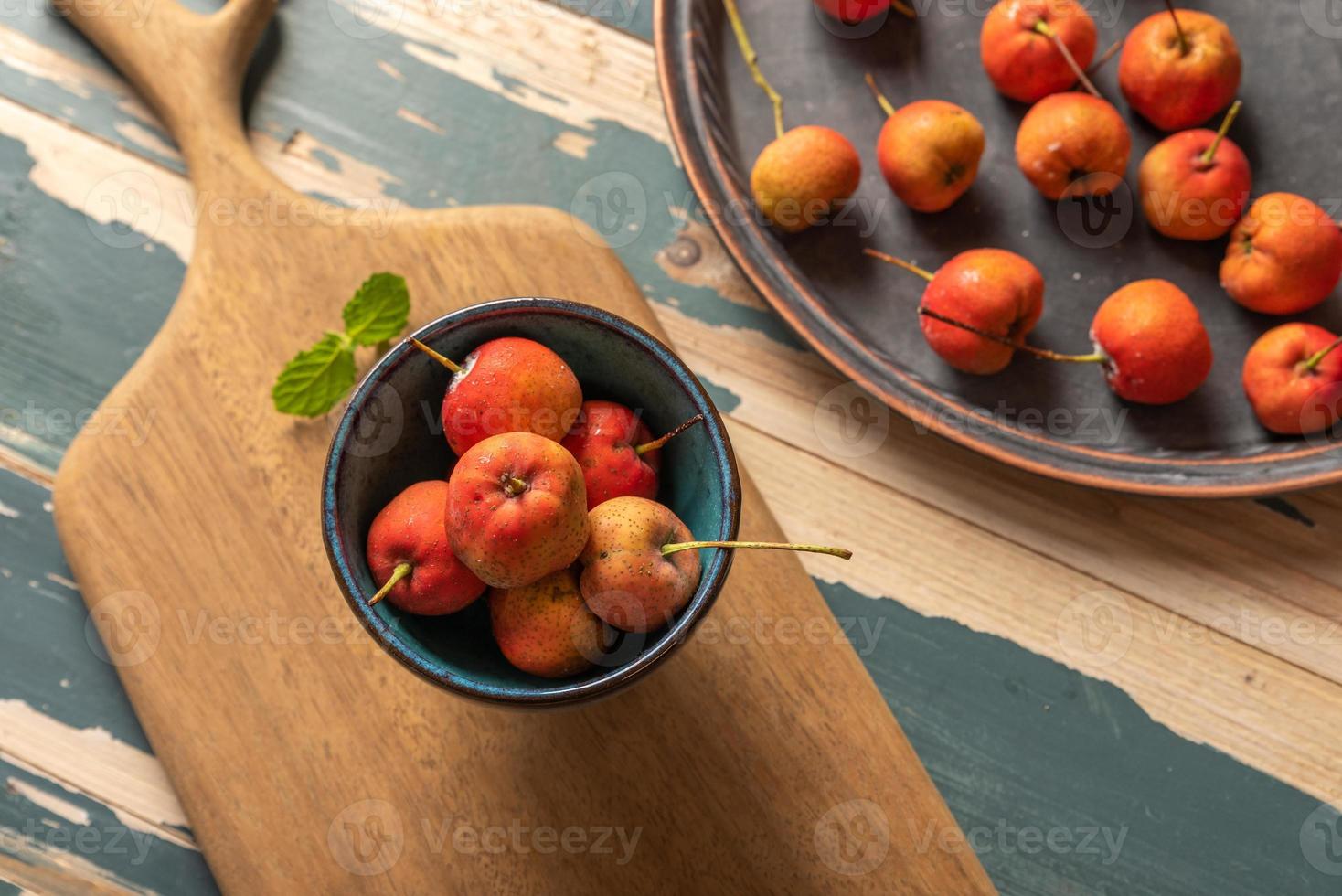 de rode meidoorn in de kom wordt op de houten tafel geplaatst foto