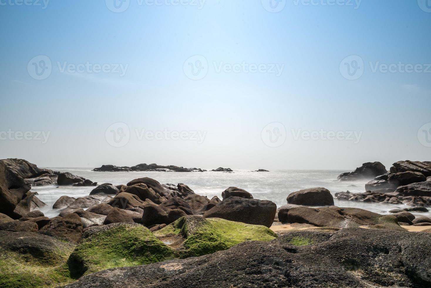 de witte golven slaan tegen de zwarte rotsen foto