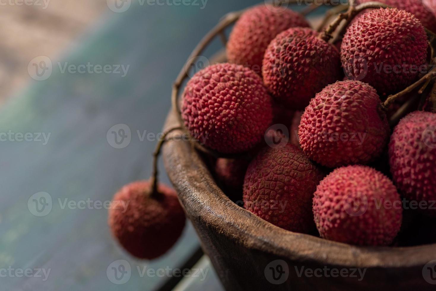 lychee wordt in een houten bord geplaatst, geschild of ongeopend, op een donkere houtnerftafel foto