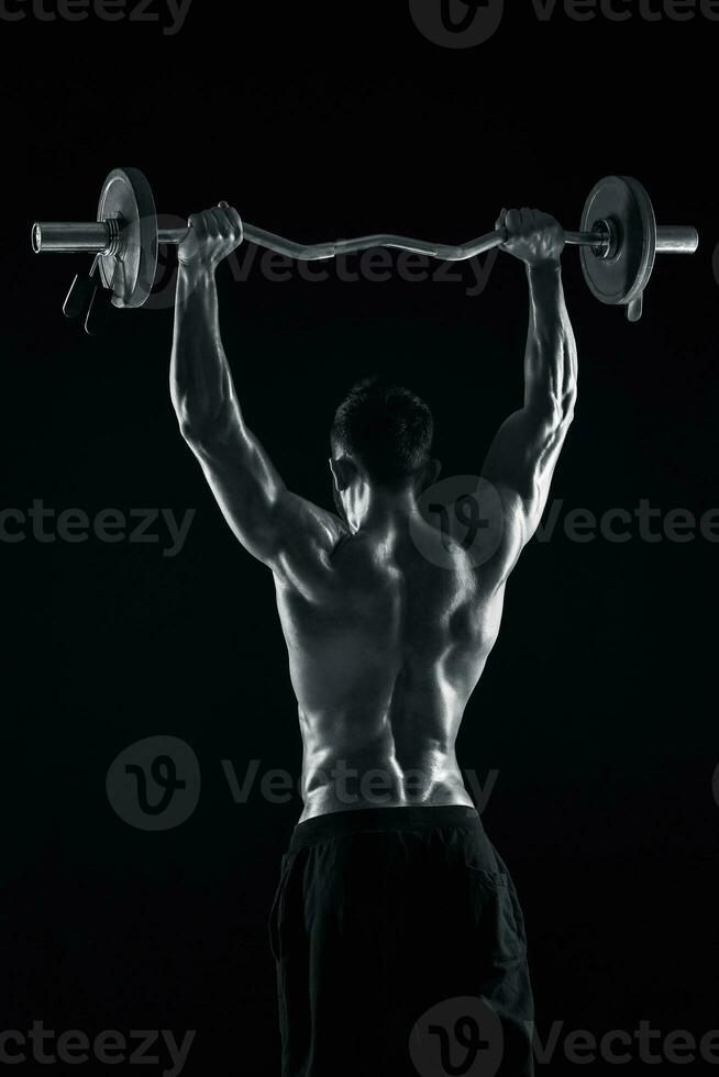 bodybuilder hijs- een barbell Aan zwart achtergrond foto