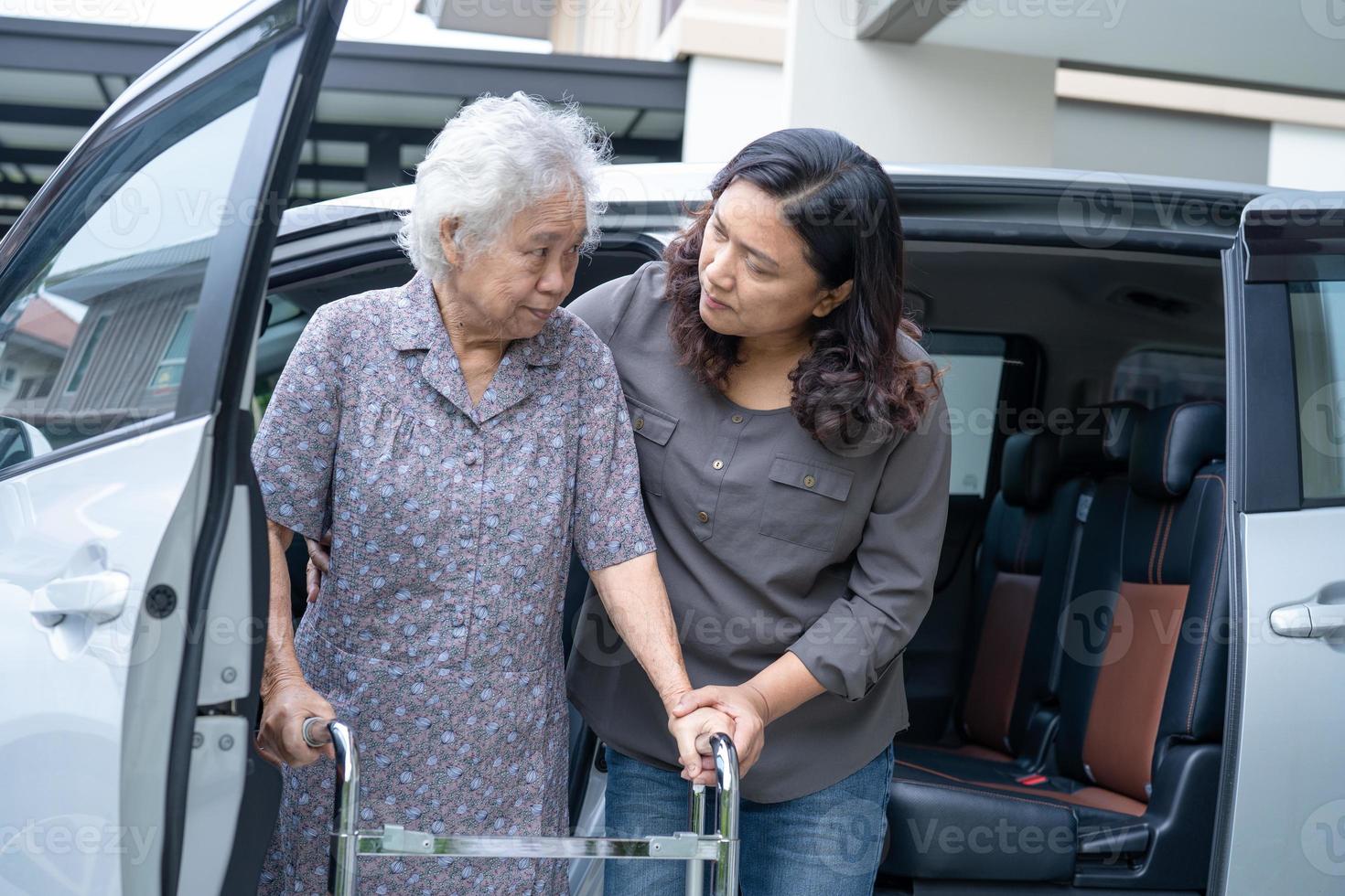 hulp en ondersteuning aziatische senior of oudere oude dame vrouw patiënt lopen met rollator voorbereiden om naar haar auto te gaan, gezond sterk medisch concept foto