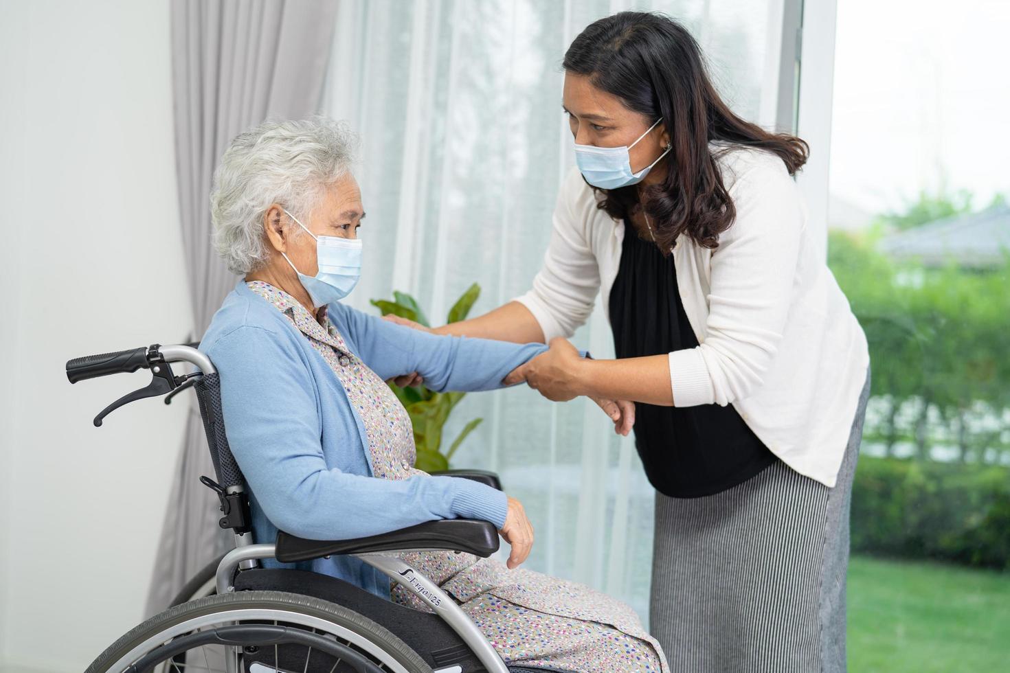 help aziatische senior of oudere oude dame vrouw zittend op een rolstoel en het dragen van een gezichtsmasker ter bescherming van de veiligheidsinfectie covid-19 coronavirus foto