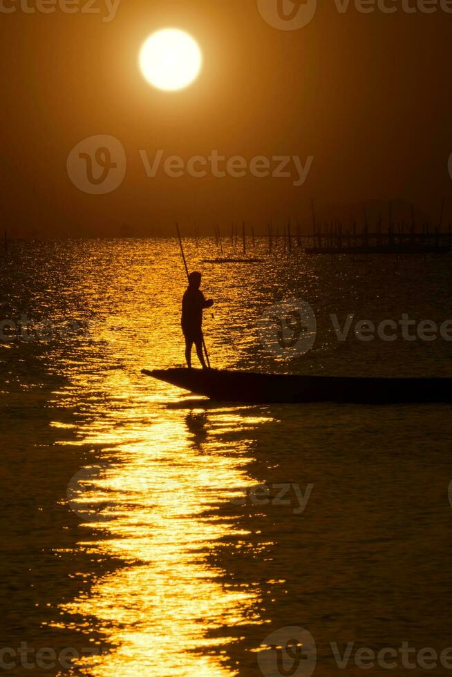 silhouet visser met zonsondergang lucht Aan de meer in zuiden van Thailand. foto