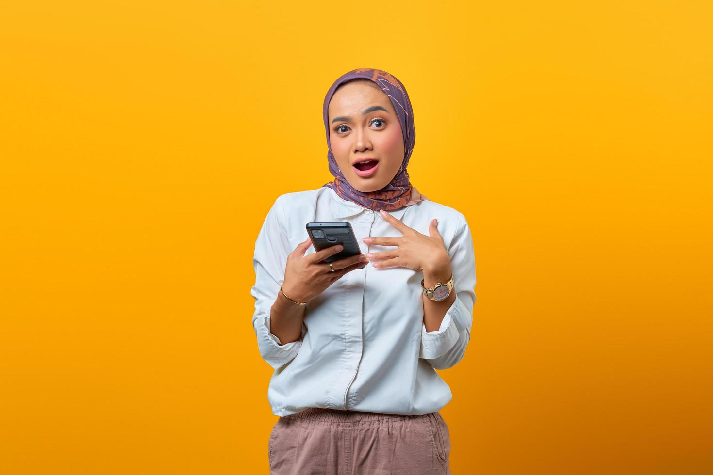 portret van verraste aziatische vrouw die mobiele telefoon met open mond gebruikt foto