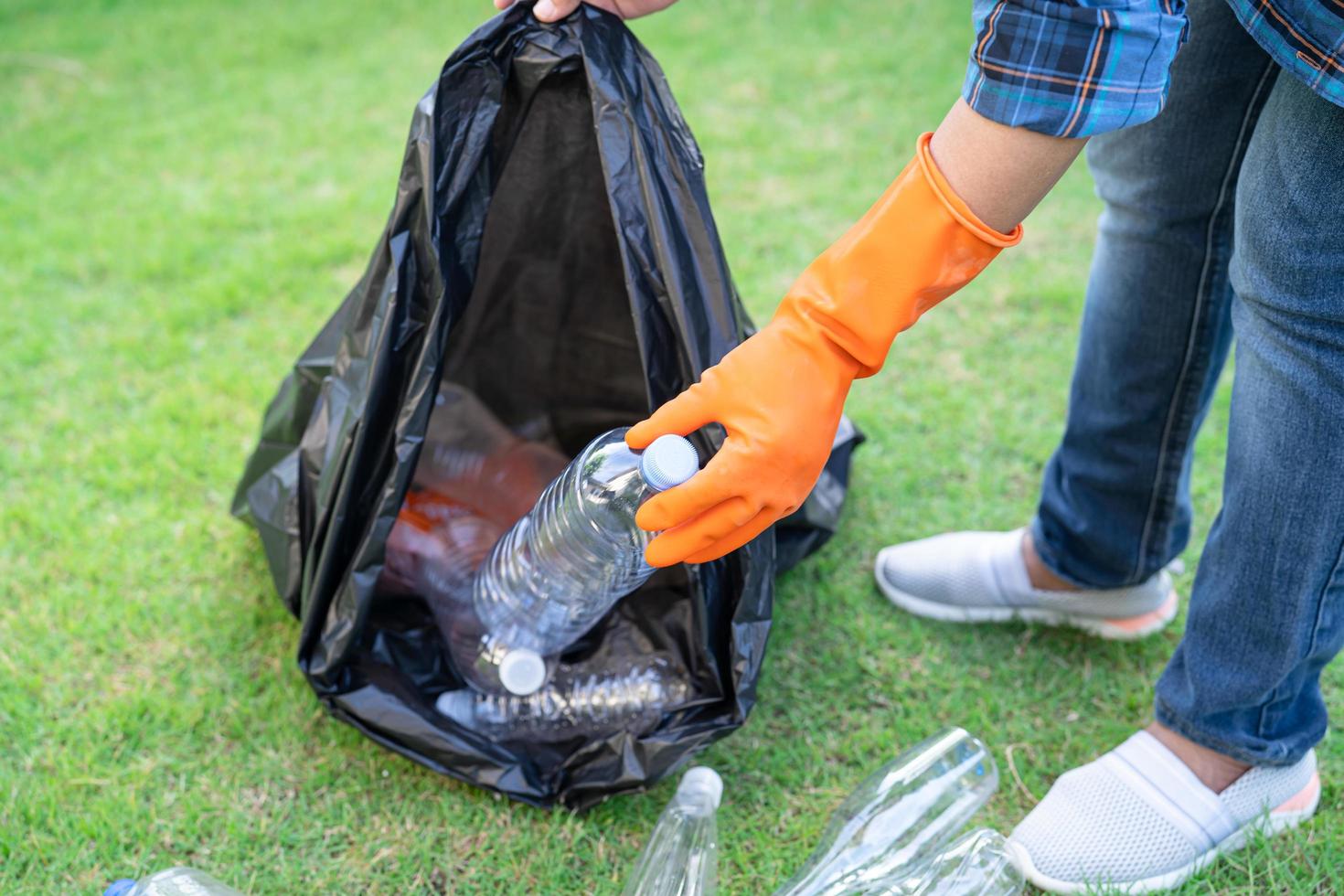 Aziatische vrouwelijke vrijwilliger draagt plastic waterflessen naar de prullenbak foto