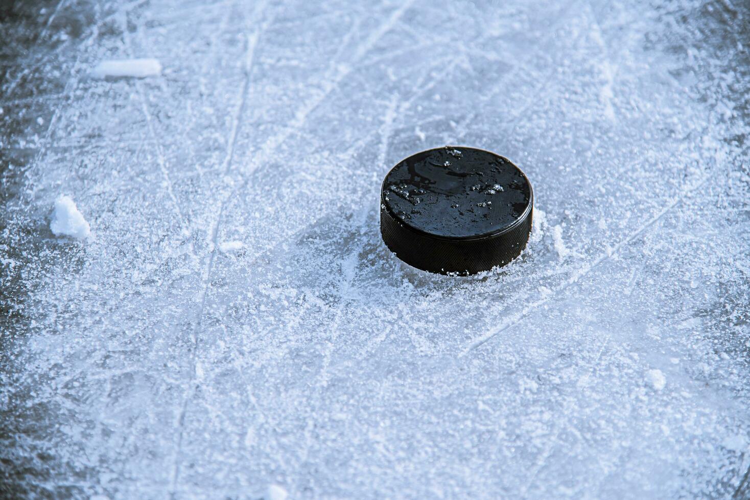 zwart hockey puck leugens Aan ijs Bij stadion foto