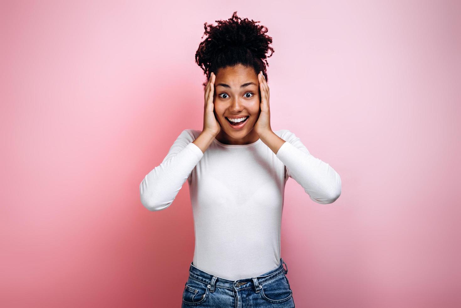 prachtig Afrikaans model dat verbazingwekkende emoties uitdrukt die in een roze studio poseren. foto