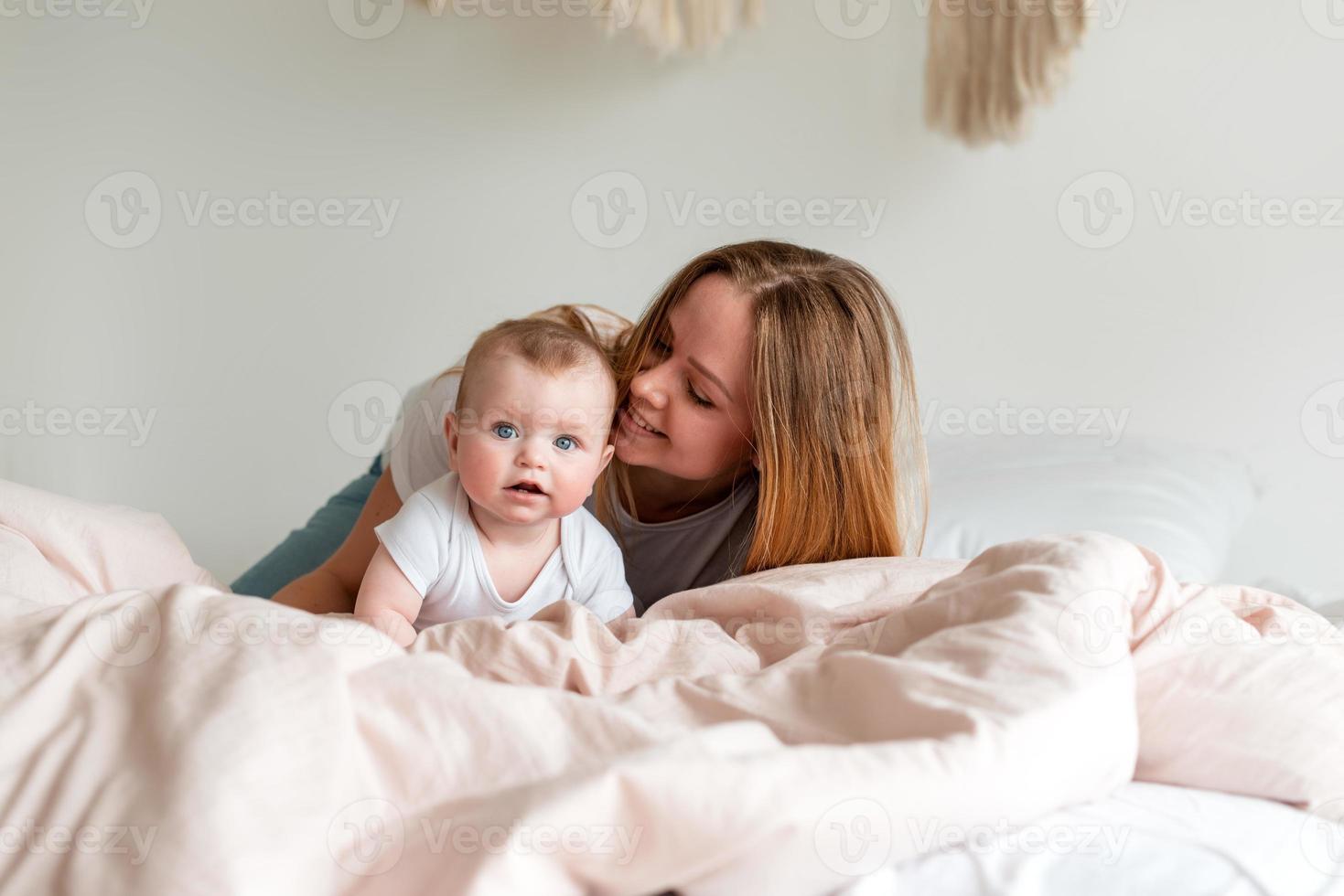 mooie jonge moeder en pasgeboren baby liggend op het bed in de slaapkamer foto