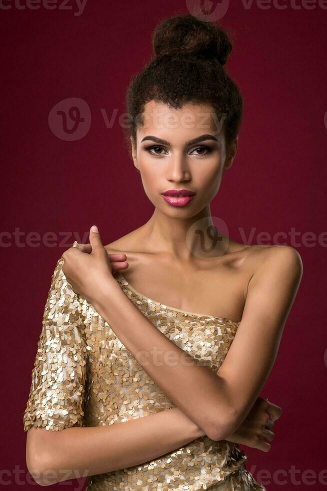 mode jong Afrikaanse vrouw met verzinnen, in sexy goud jurk. foto