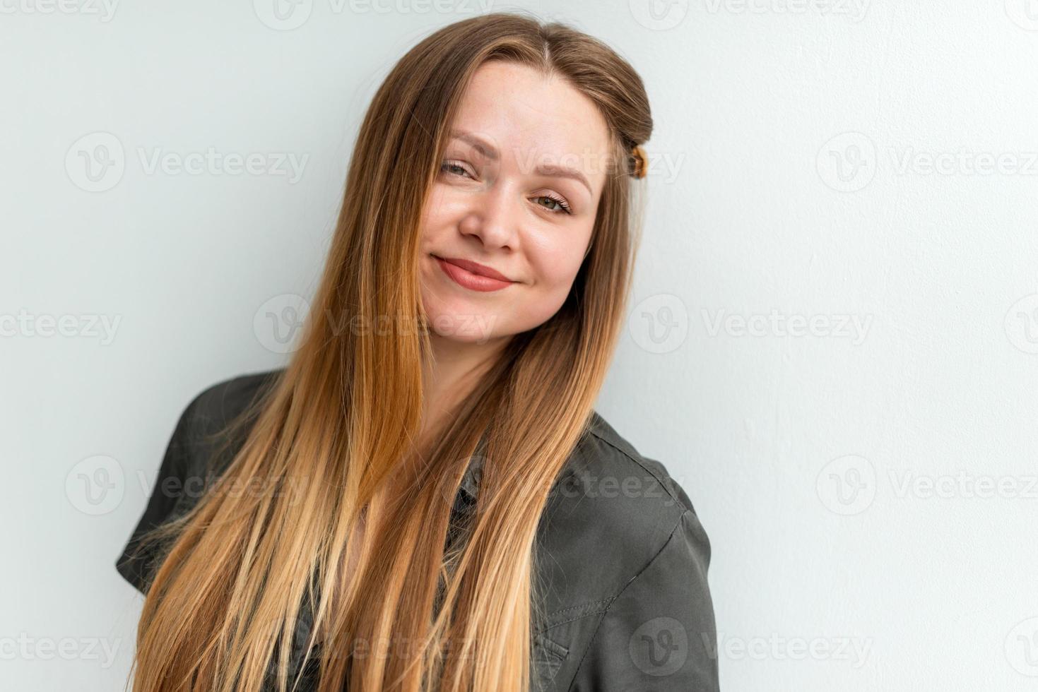 aantrekkelijke, schattige jonge vrouw die zich voordeed op een witte muur achtergrond foto