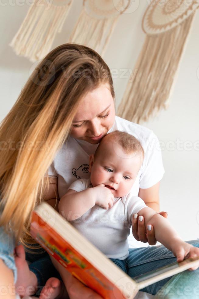 een jonge vrouw leest een boek voor aan haar kleine, schattige, mooie dochter foto