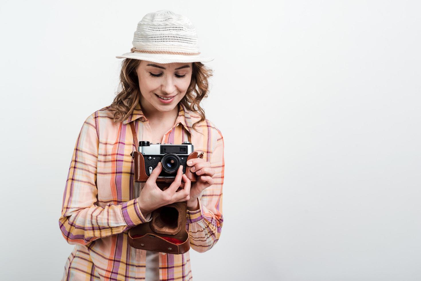 portret van een gelukkig meisje in hoed die retro camera over witte studioachtergrond gebruiken foto