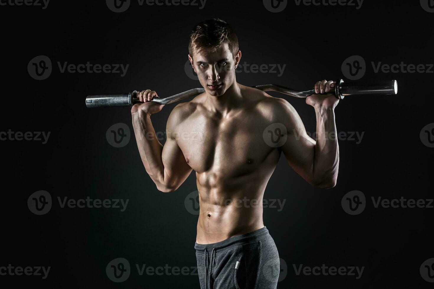 sterk Mens Holding barbell Aan zijn schouders, op zoek Bij camera foto