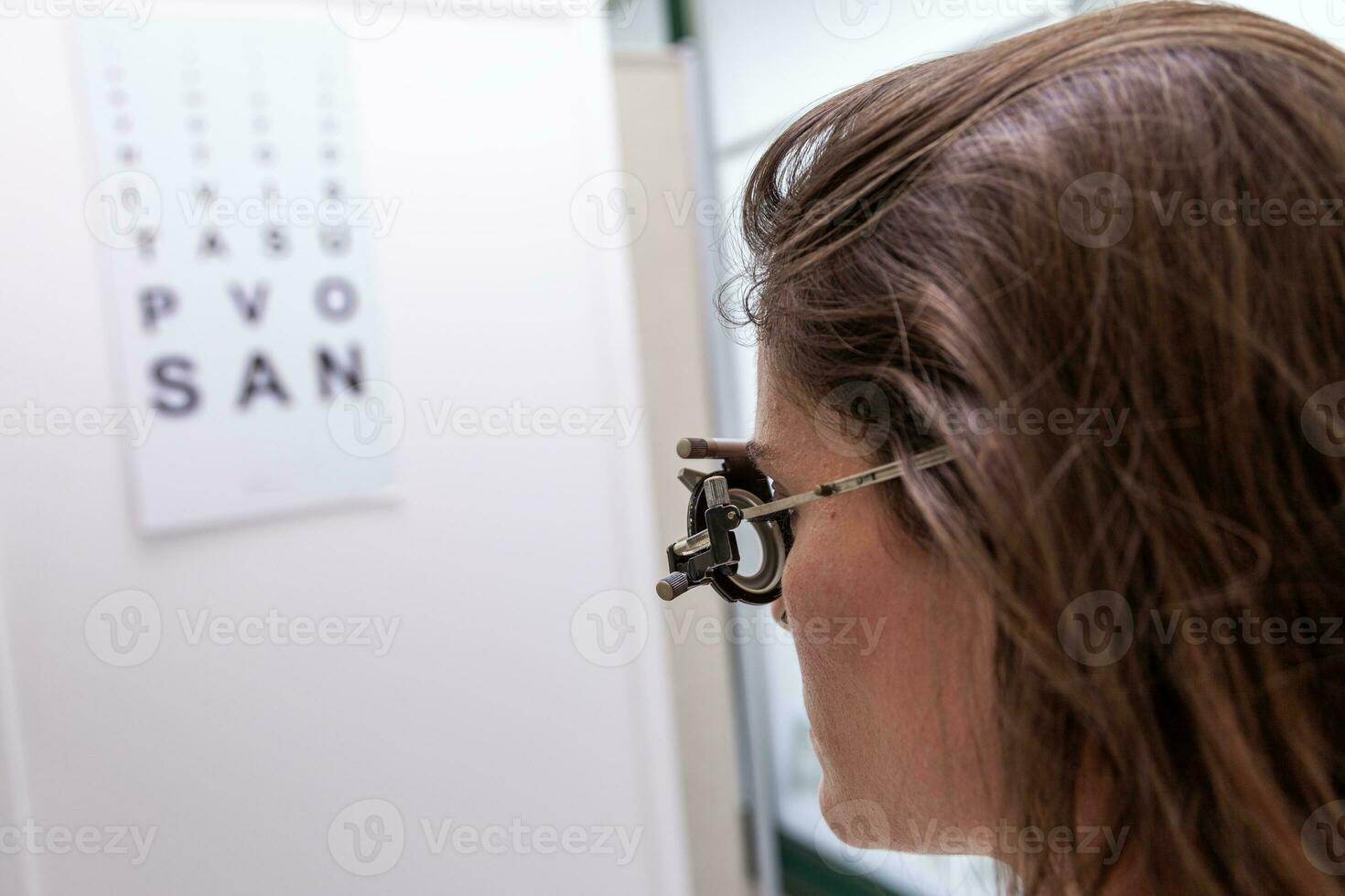 mooi vrouw testen nieuw hulp lenzen met phoropter gedurende een oog examen foto