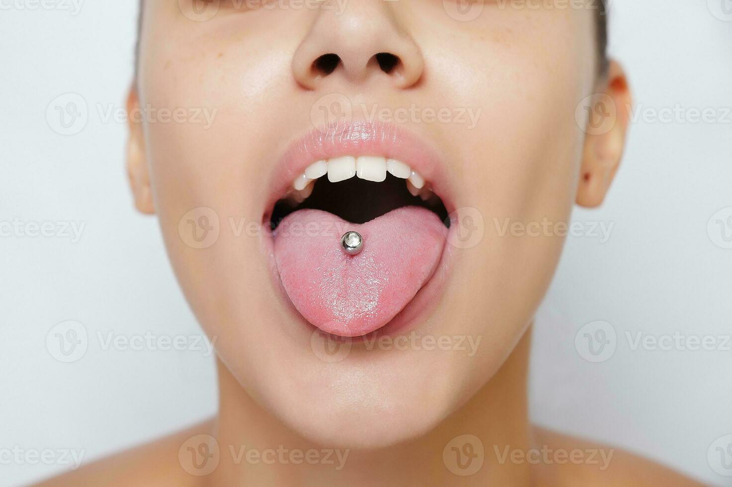 mooie vrouw steekt haar tong uit en toont jonge piercing foto