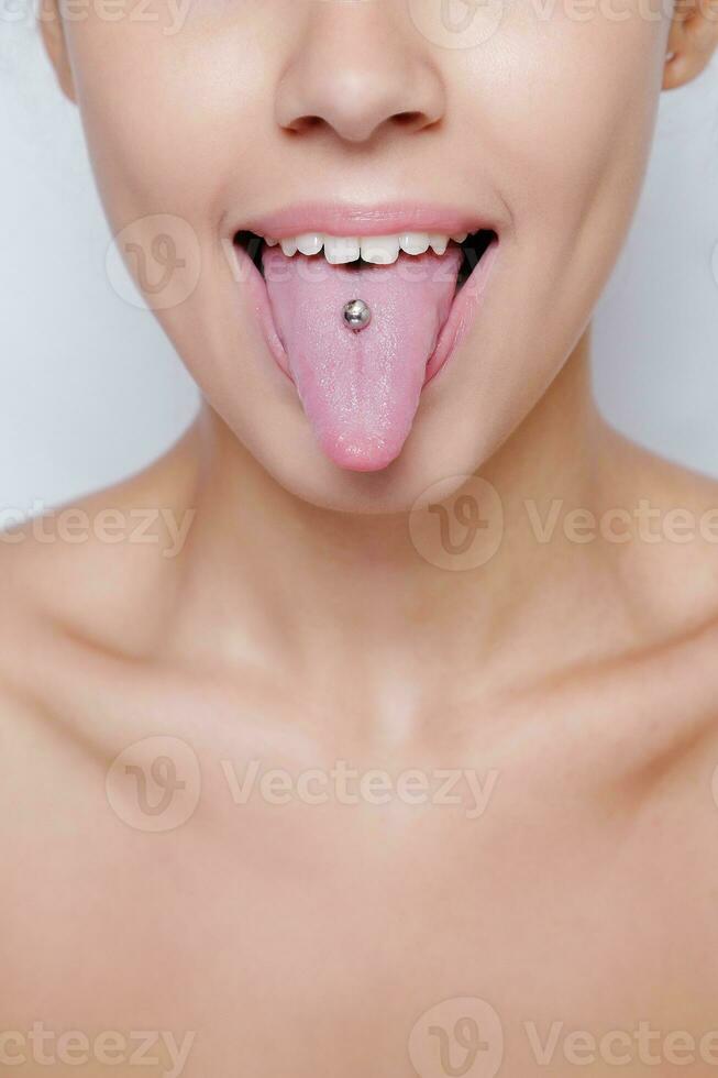 mooie vrouw steekt haar tong uit en toont jonge piercing foto