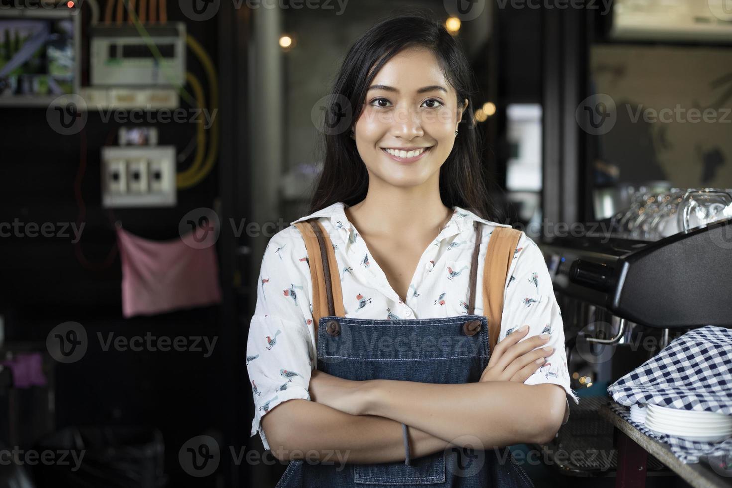 aziatische vrouwenbarista glimlacht en gebruikt koffiemachine in coffeeshopteller - werkende vrouw, eigenaar van een klein bedrijf, eten en drinken caféconcept foto