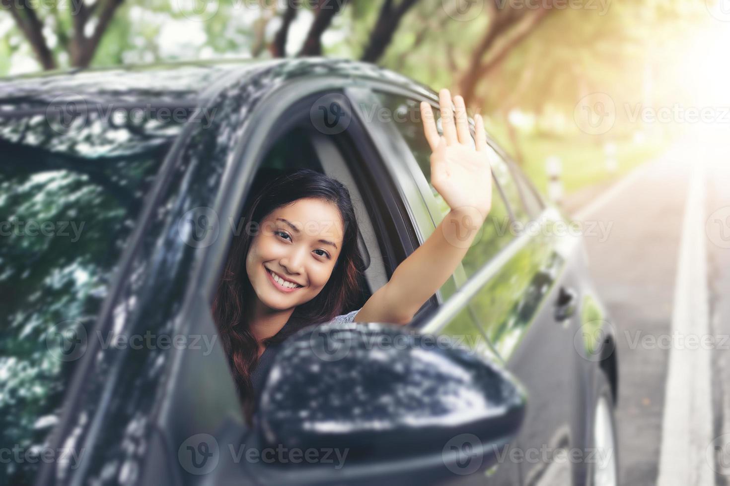 mooie aziatische vrouw die lacht en geniet van een auto op de weg rijden om te reizen foto