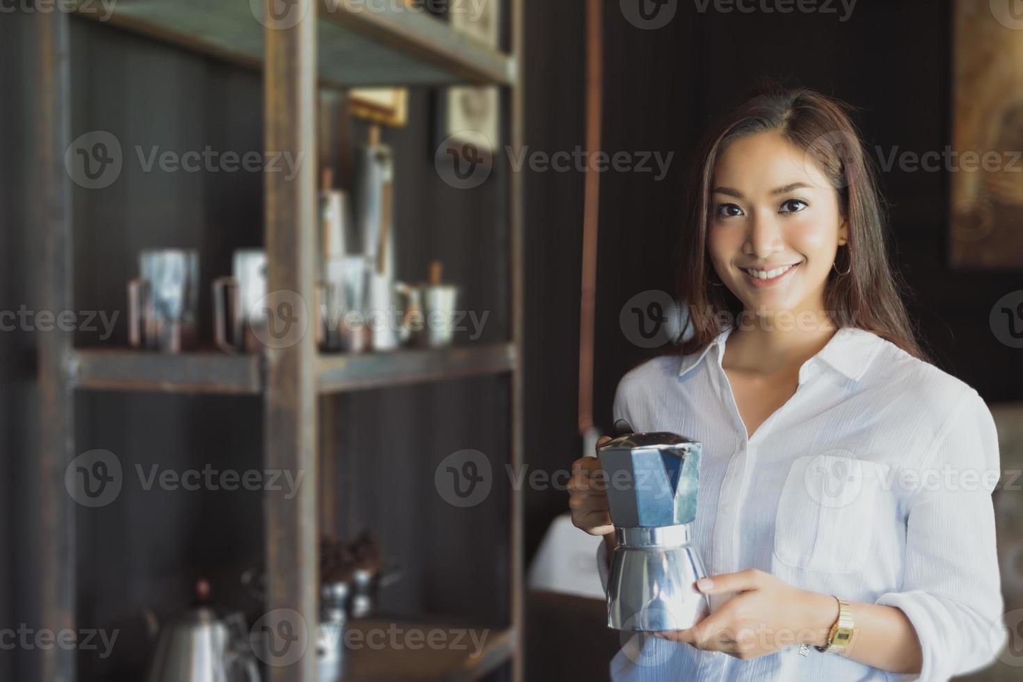 Aziatisch meisje staat met een koffiepot-glimlach en veel plezier met ontspannen in een coffeeshop na het werken in een succesvol kantoor. foto