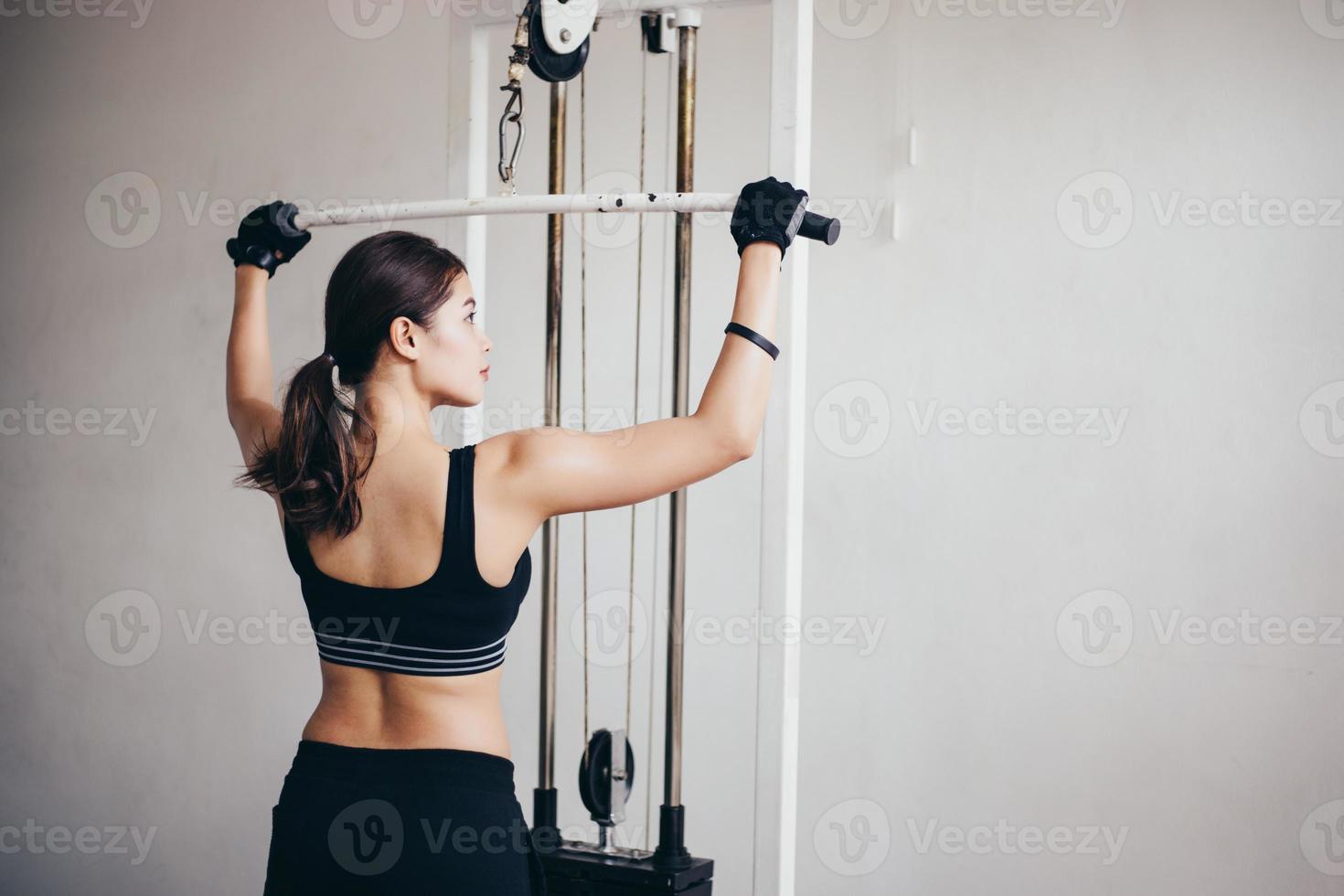 mooie gespierde fitte vrouw die spieren bouwt en fitness vrouw die oefeningen doet in de sportschool. fitness - concept van gezonde levensstijl foto