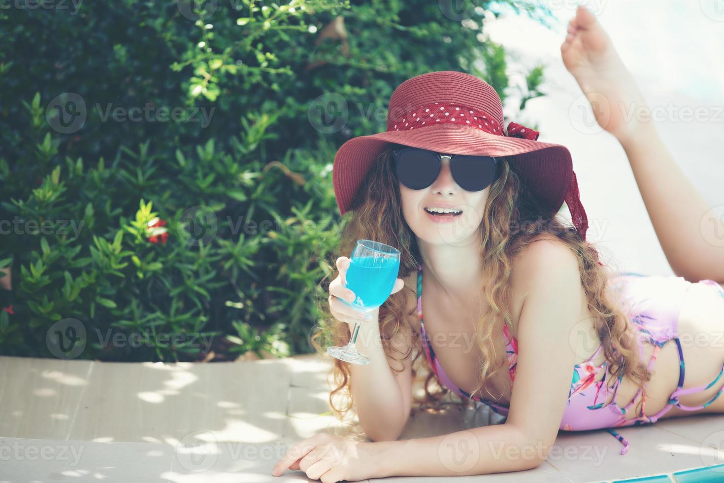 vrouwen dragen bikini's en drinken cocktails in de hete zomer bij het zwembad. foto