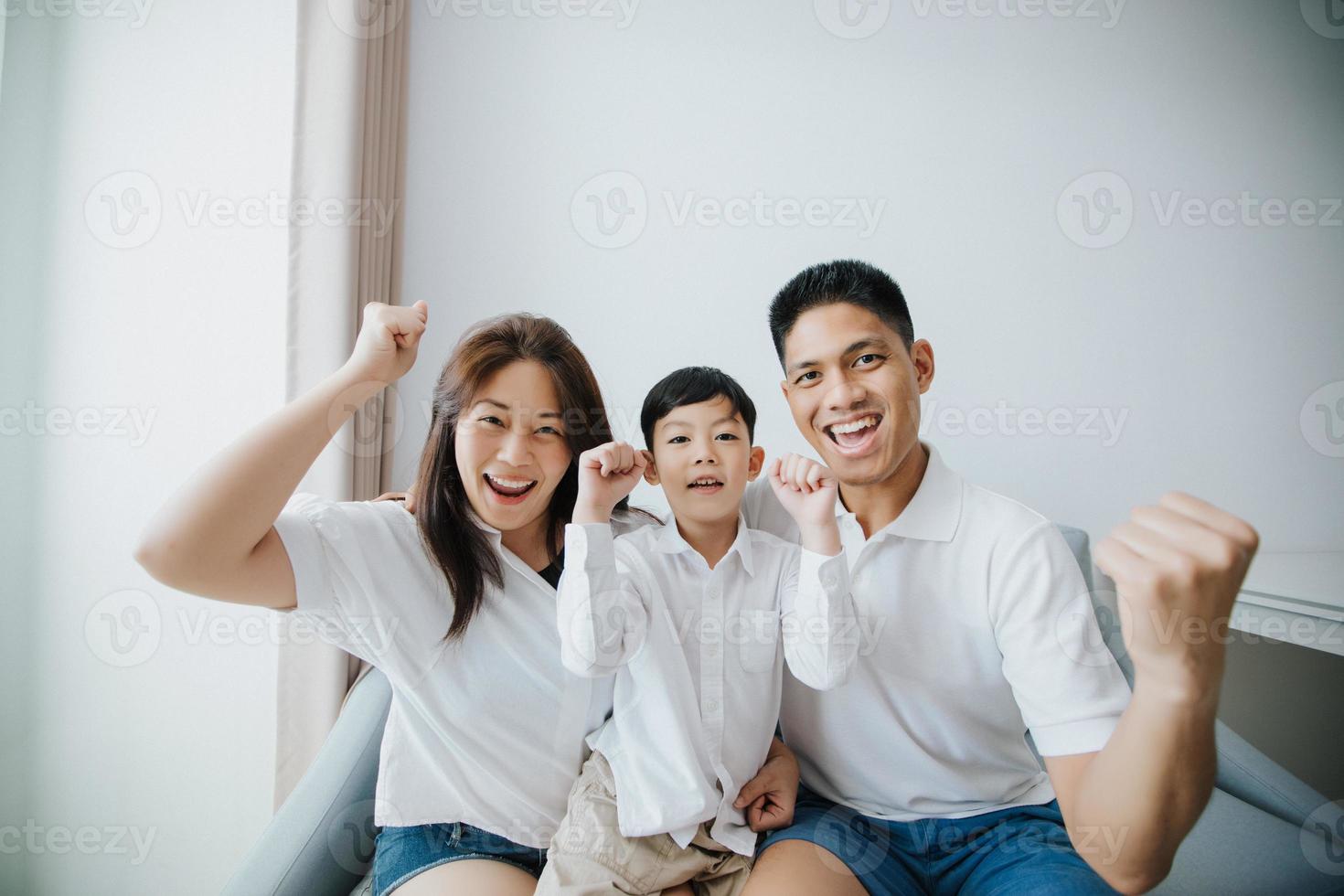 opgewonden en gelukkig gezin met opgeheven armen terwijl ze thuis televisie kijken foto