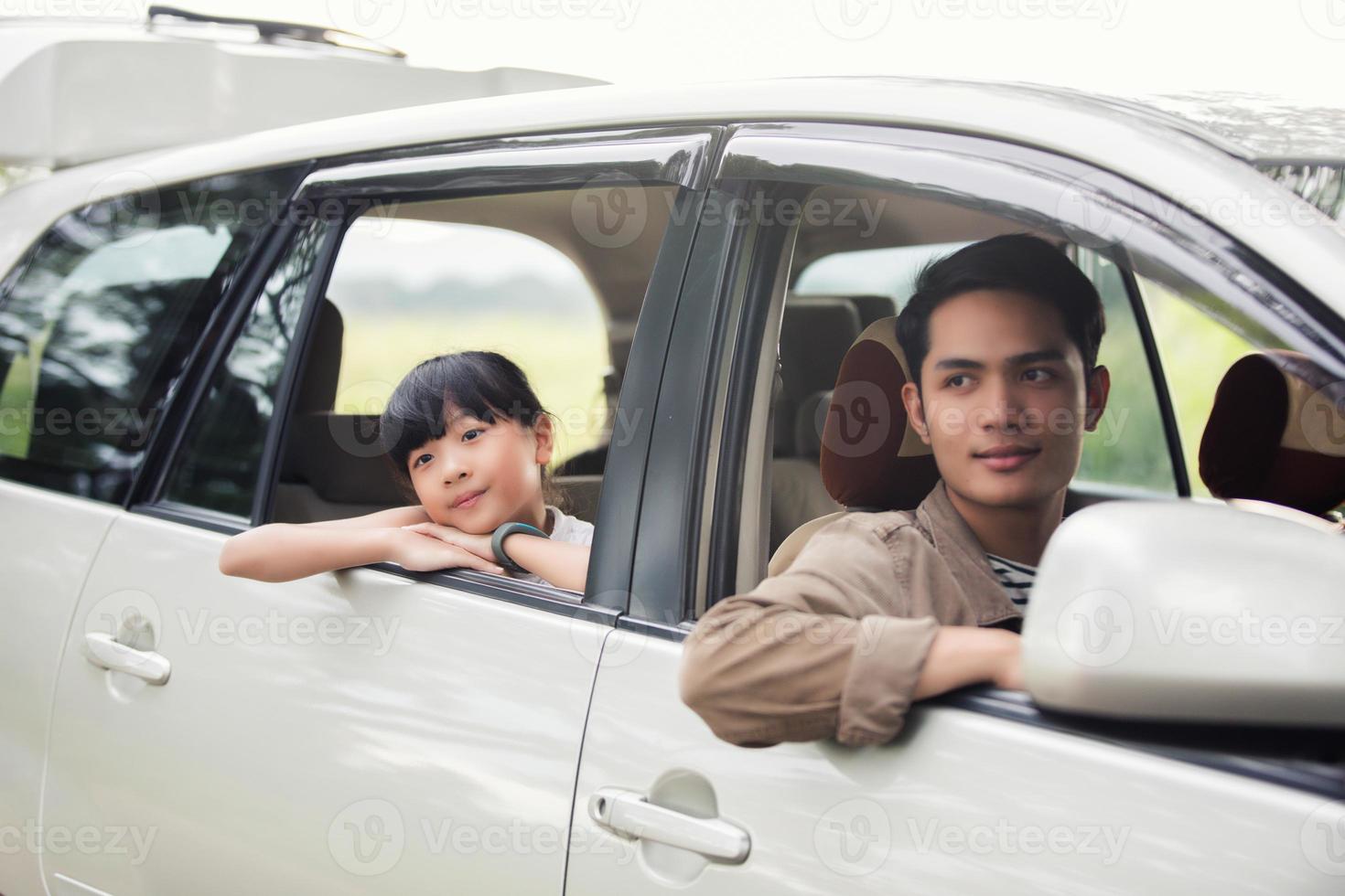 gelukkig klein meisje met aziatische familie die in de auto zit om te genieten van een roadtrip en zomervakantie in een camper foto