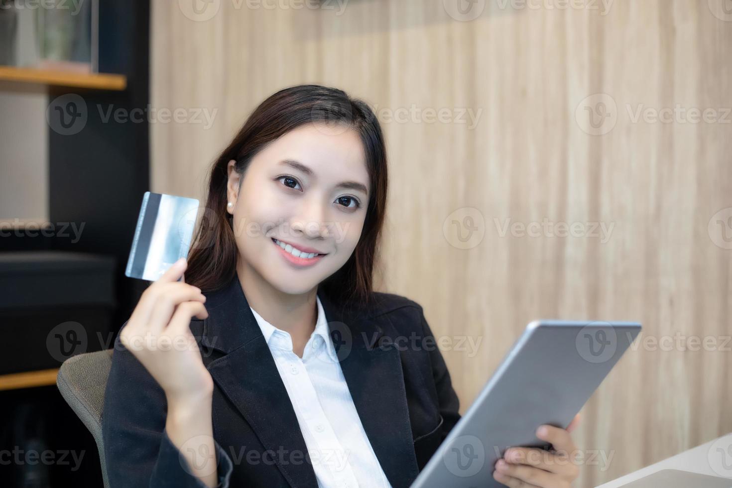 Aziatische vrouw die tablet en creditcard gebruikt om online te winkelen foto