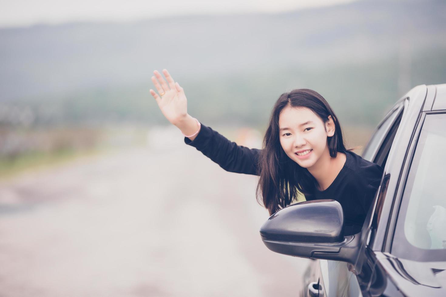 mooie aziatische vrouw die lacht en geniet van een auto op de weg rijden om te reizen foto