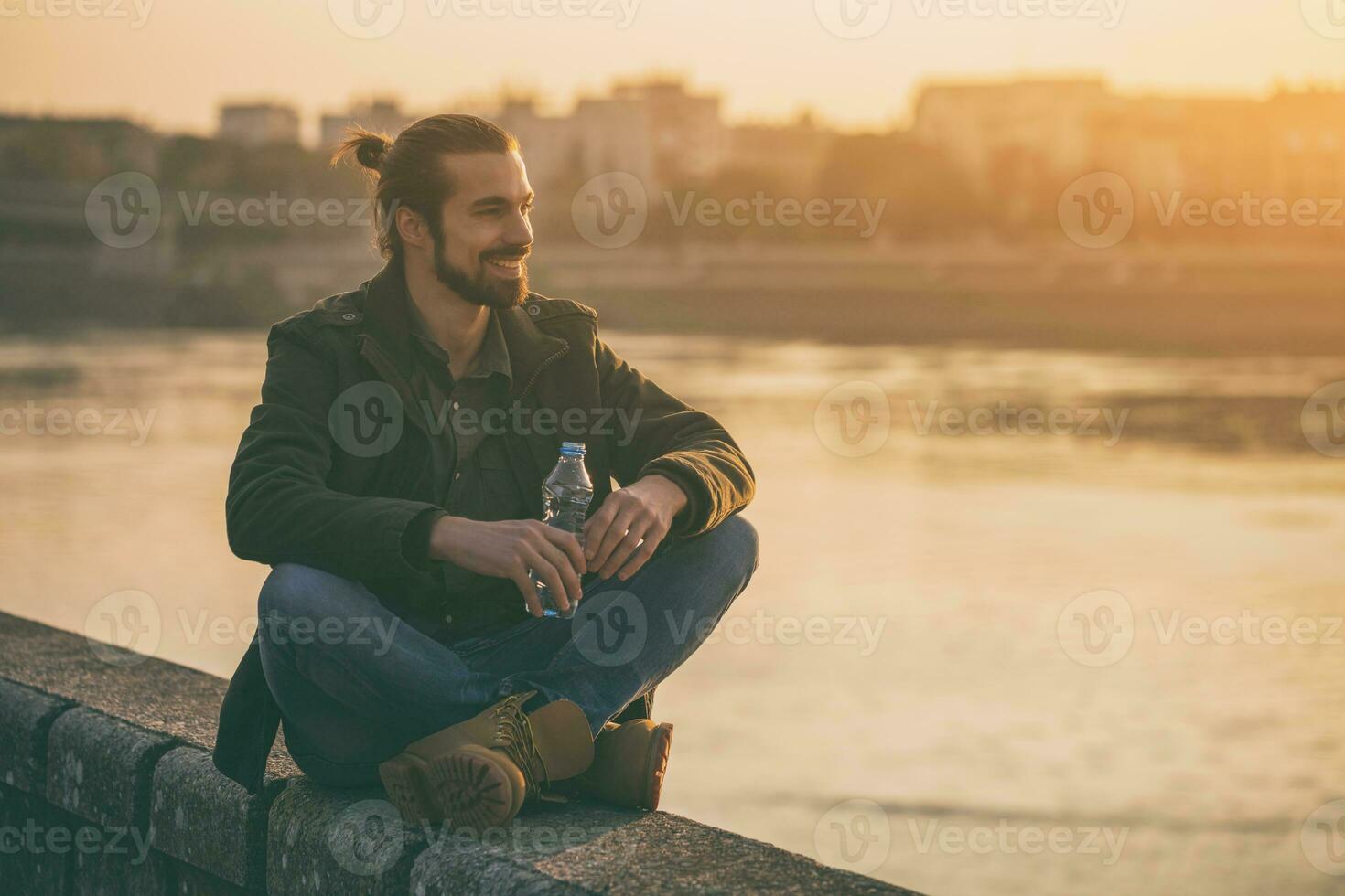 knap modern zakenman geniet drinken water en resting door de rivier.afgezwakt afbeelding. foto