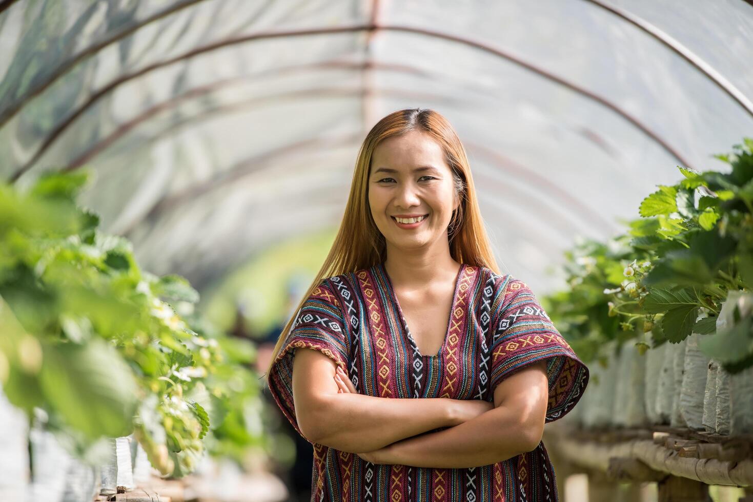 mooie boerenvrouw die aardbeienboerderij controleert foto